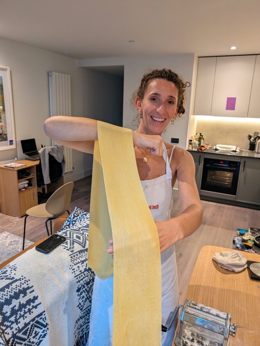 A guest holding up a sheet of fresh pasta she has just rolled in a lesson at home
